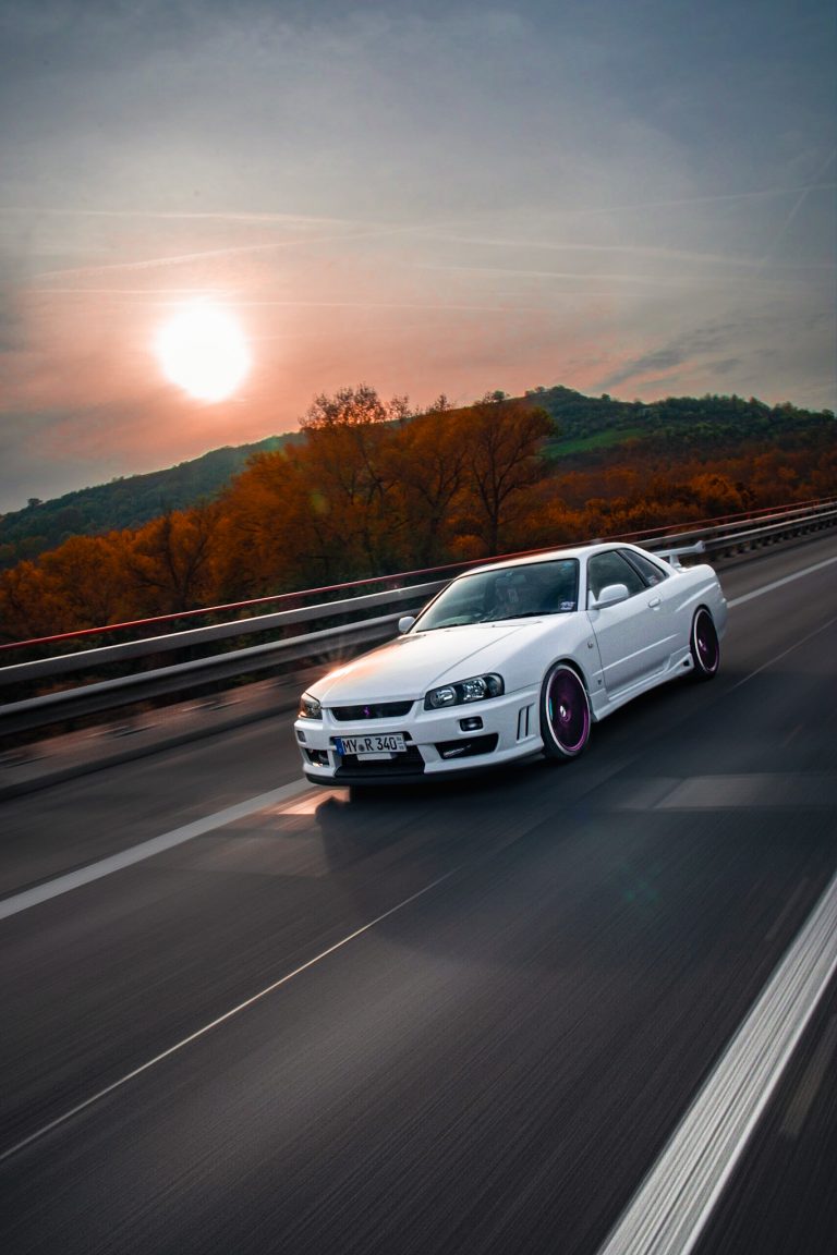 Ein weißer Nissan Skyline R34 GTT in eine Rolling Fahrende Szene beim Sonnenuntergang. Foto von Tobias Küpper - pandalor